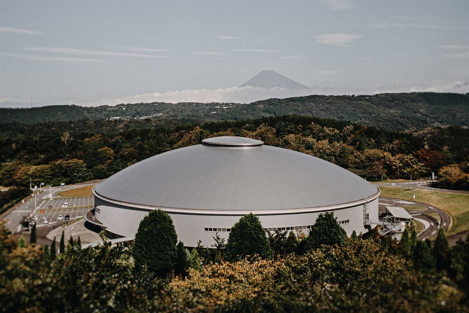 Exterior view of Izu Velodrome sitting amongst the forest and Mount Fuji in Japan