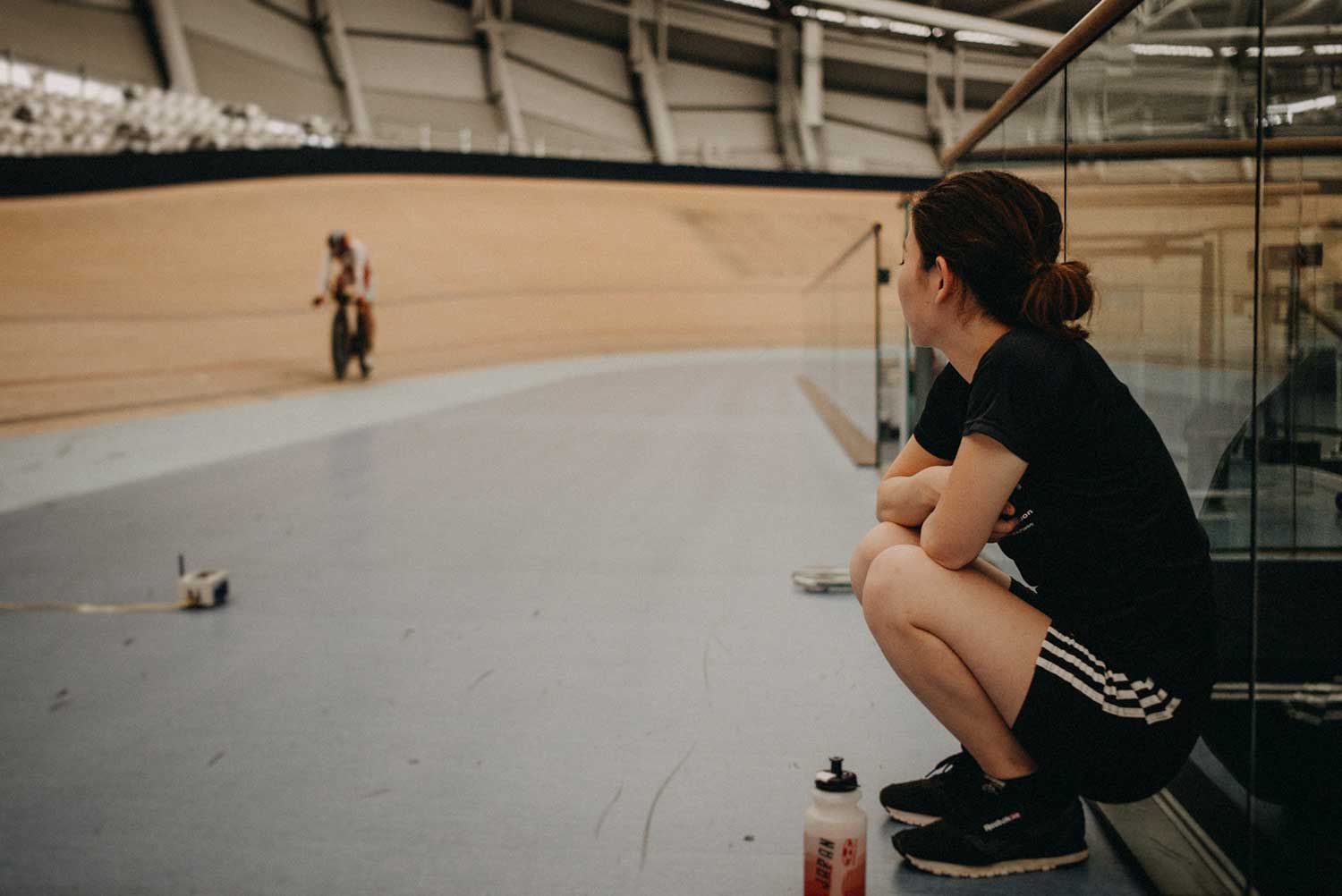Cycling Physiotherapist watches cyclist training on the velodrome