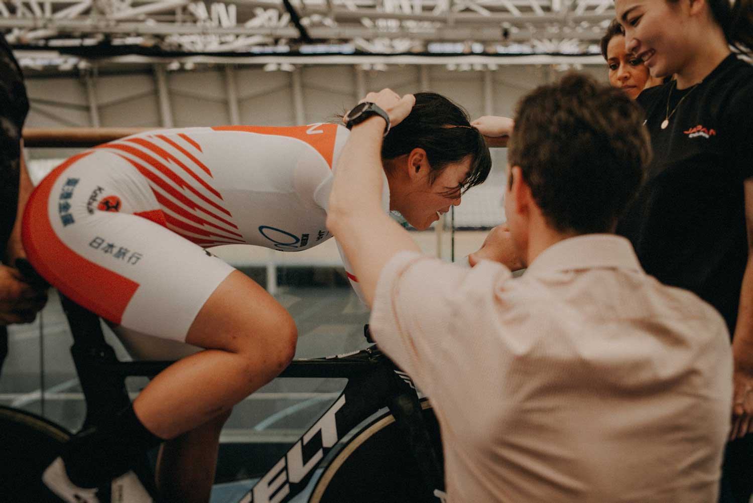 Cycling biomechanist adjusts body position of Japanese track cyclist during training session at velodrome