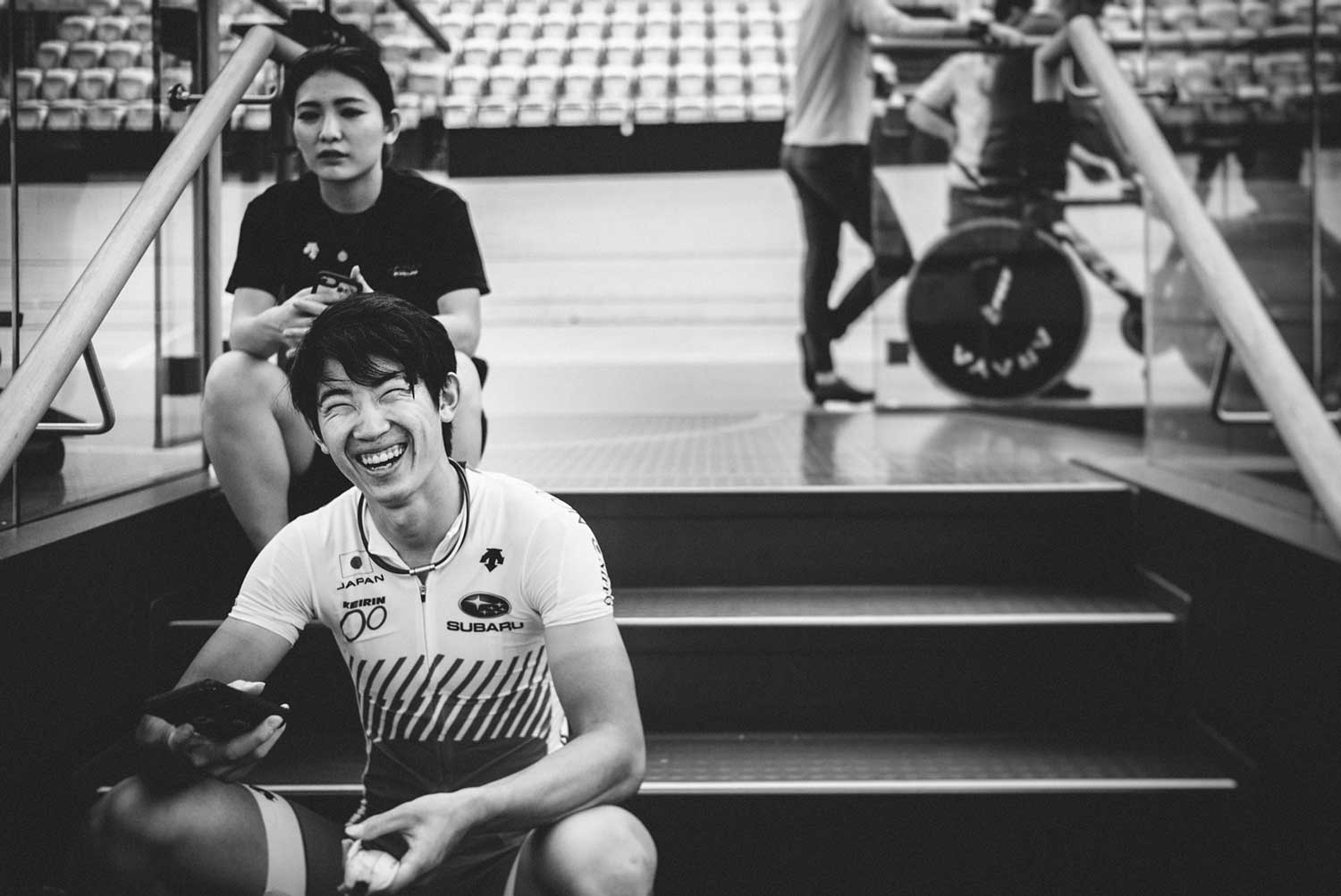 Japanese track cyclist laughs whilst having a break at velodrome during trainin session