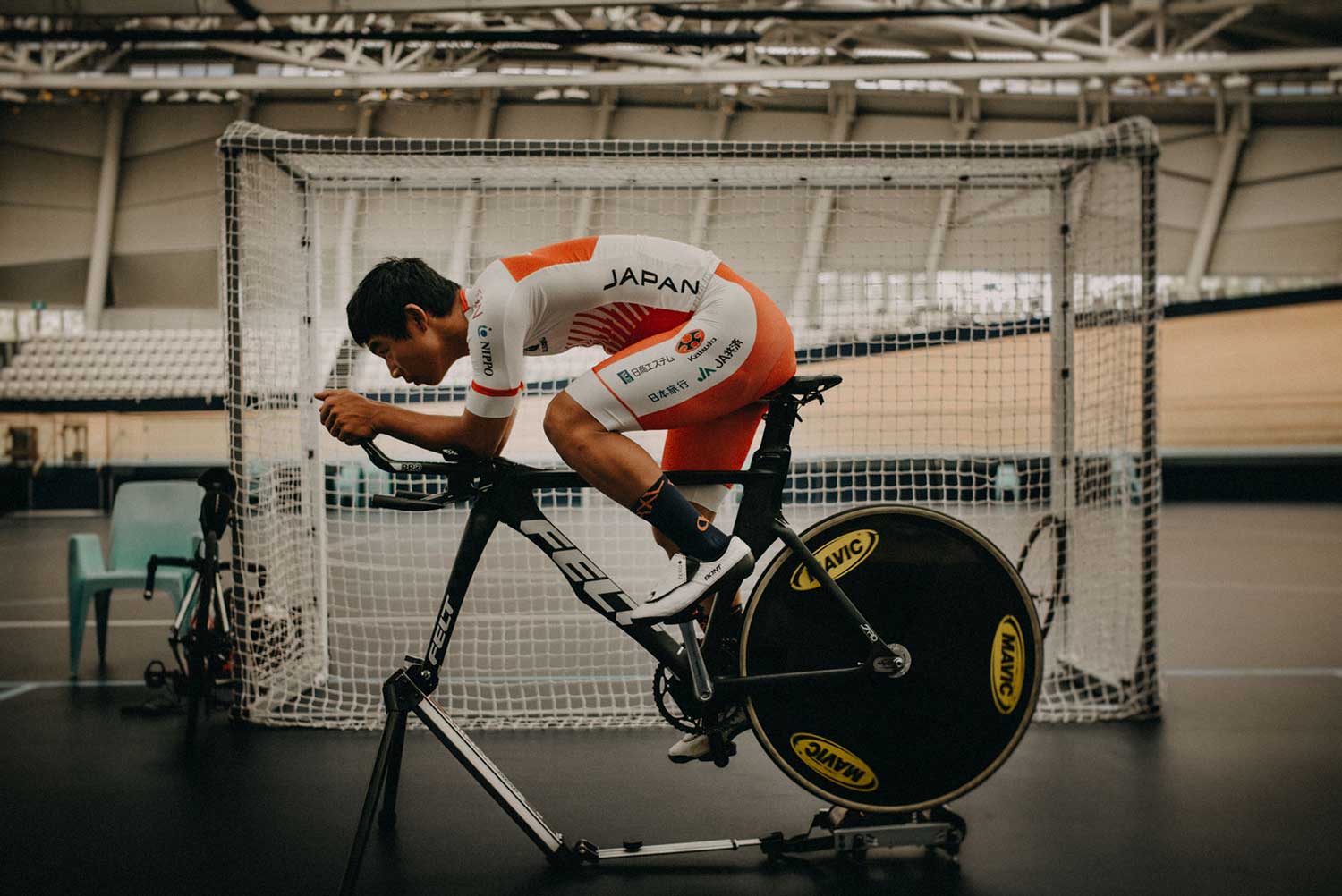 Japanese track cyclist trains on static bike with aerobars at velodrome during training session