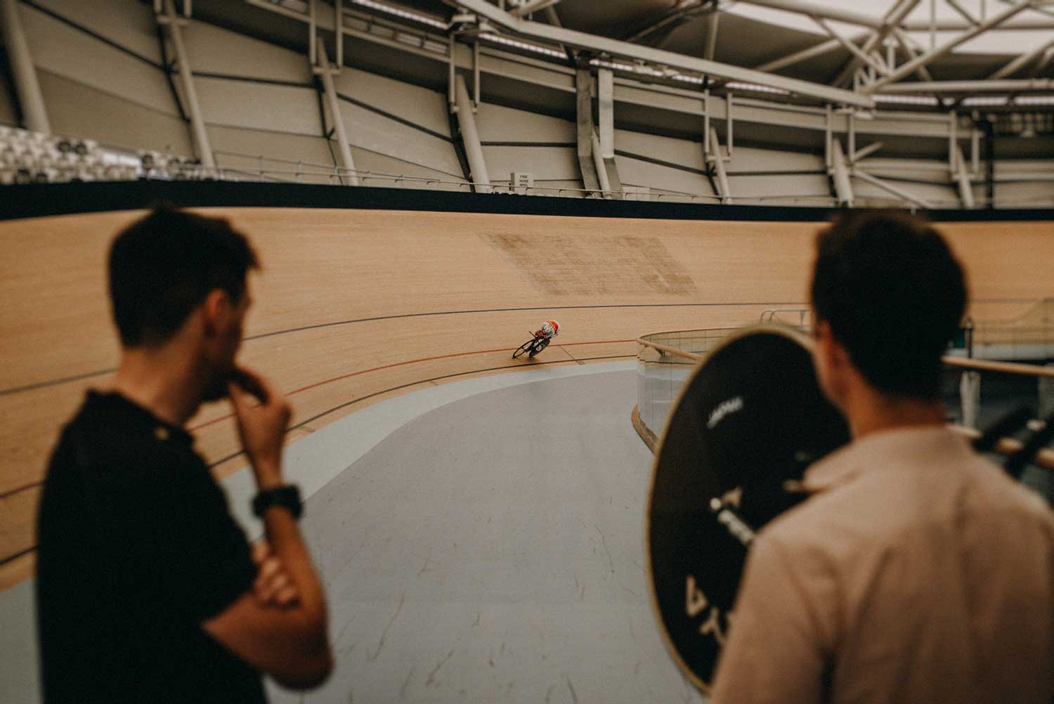 Japanese cyclist training for individual time trail in velodrome with coaches watching